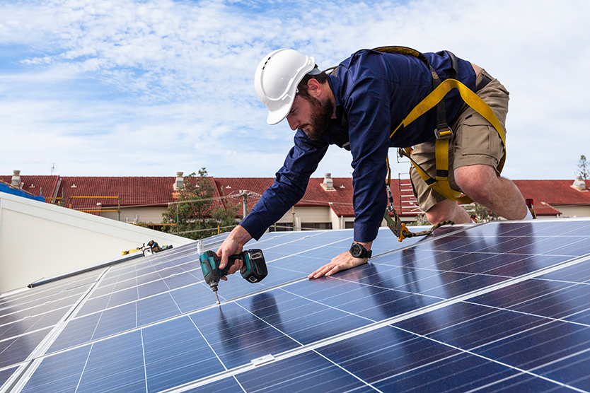 Arbeiter instaliert Sonnenkollektoren auf Hausdach zur Energiewende Plattform Gebäude; Quelle: iStock.com/zstockphotos