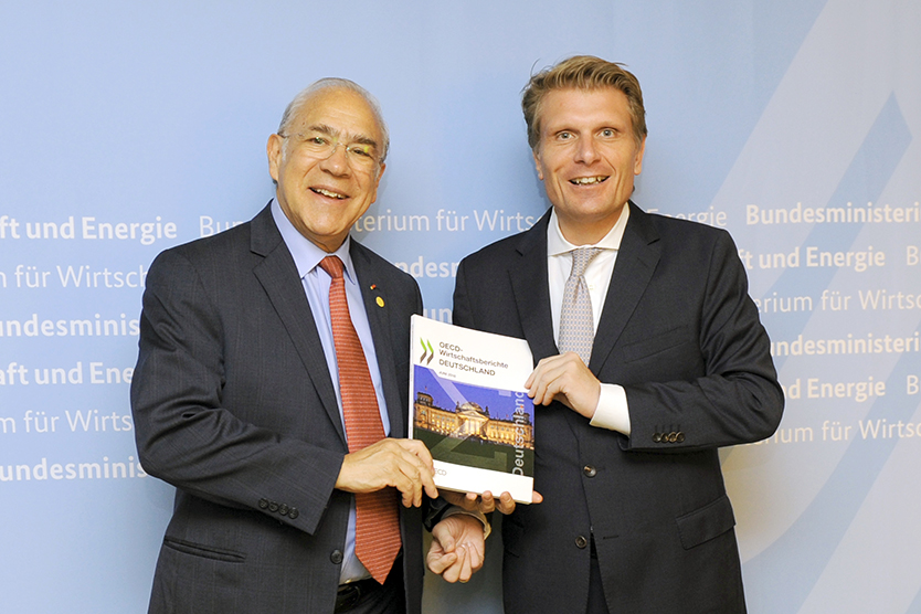 OECD-Generalsekretär Angel Gurría (links) übergibt den OECD-Bericht an den Parlamentarischen Staatssekretär Thomas Bareiß (rechts)