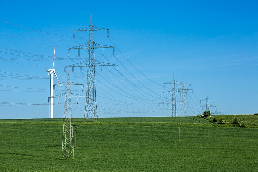 Des poteaux électriques et des éoliennes illustrant le sujet de l'énergie